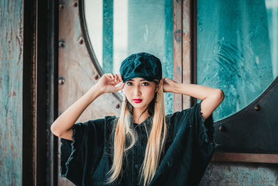 Portrait of young woman standing against door