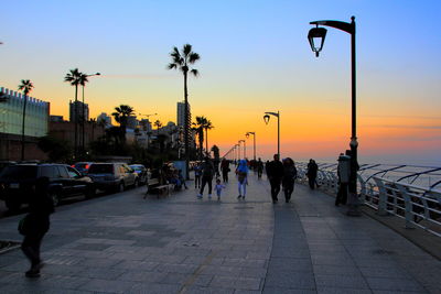 People walking on road at sunset