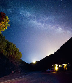 Cars on illuminated road against sky at night