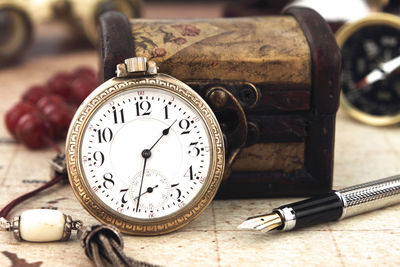 Close-up of pocket watch with box and pen on table