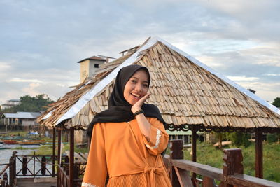 Portrait of smiling woman standing against sky