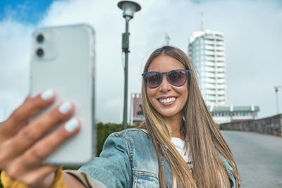 Portrait of young woman standing against sky