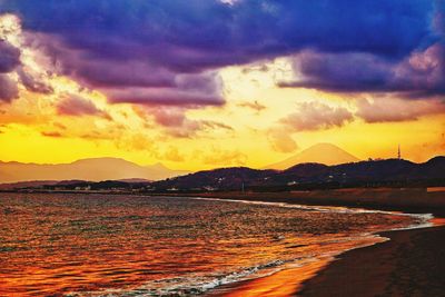 Scenic view of sea against dramatic sky during sunset