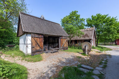 Old house on field by trees against sky