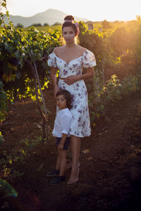 Family mother in a dress with her son walking through a vineyard in summer in italy