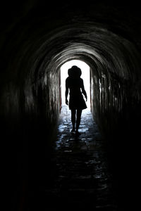 Rear view of silhouette man standing in tunnel