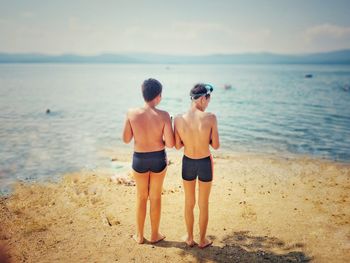 Rear view of friends standing on beach