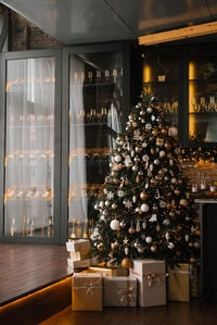 Beautiful christmas tree decorated with gold and silver toys and gift boxes for days in a cozy house