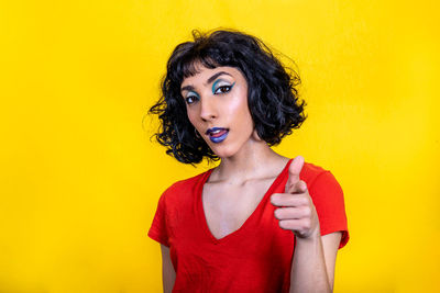 Smiling young woman in red t-shirt is pointing at you. 