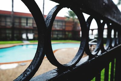 Close-up of railing by swimming pool against sky