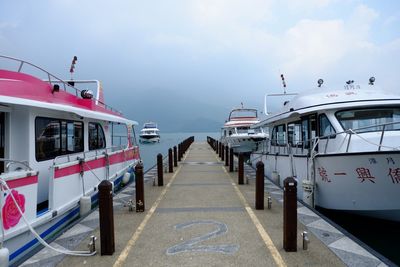 Boats moored by jetty on sea against sky