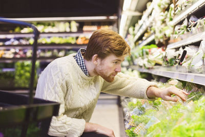 Young man shopping vegetables at supermarket