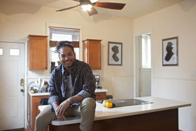 Young man sitting on a kitchen bench.