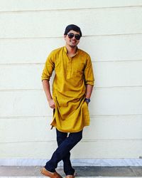 Full length of man wearing sunglasses standing against wall