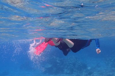 Underneath view of people swimming in sea