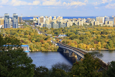 Bridge over river by buildings in city against sky