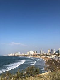 Sea and buildings against clear blue sky