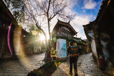 Rear view of backpacker standing against building in town