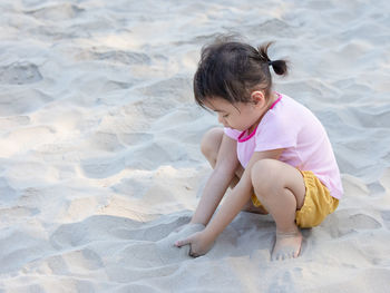 High angle view of boy playing with sand at beach