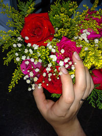 Close-up of hand holding multi colored flowers