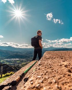 Man standing on mountain against sky on sunny day