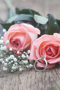 Close-up of pink roses and wedding ring on table