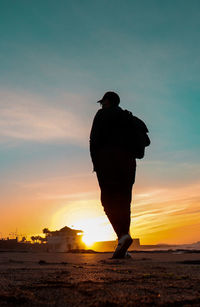 Rear view of silhouette man standing on street during sunset