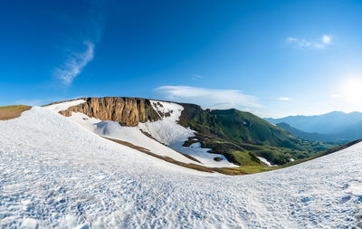 Scenic view of snowcapped mountains against blue sky