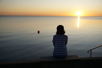 Rear view of silhouette man against sea during sunset