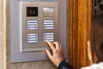 Close-up of woman using intercom on wall