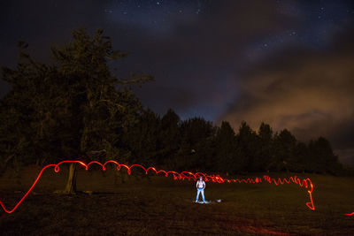 Man on illuminated tree against sky at night