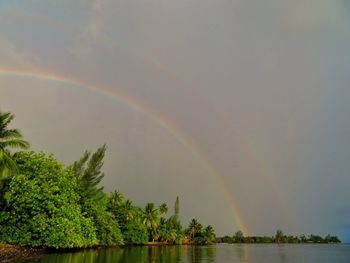 Scenic view of rainbow over lake against sky