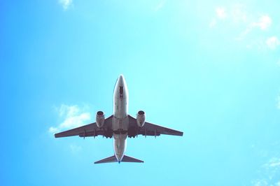 Low angle view of airplane flying against clear blue sky