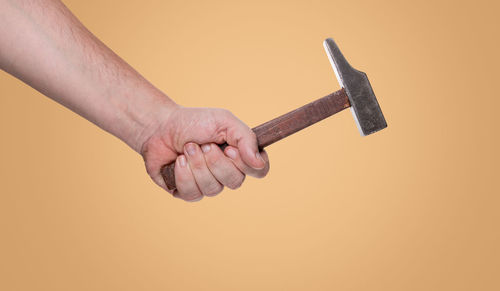 Close-up of hand holding cigarette against white background