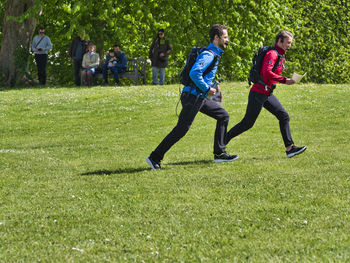 Rear view of people running on grass