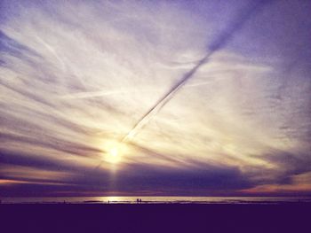 Sun shining through clouds over sea