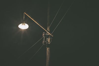 Low angle view of illuminated lighting equipment against sky at night