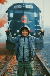 Portrait of boy standing by railroad tracks during winter