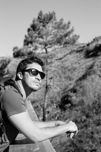 Young man wearing sunglasses standing against sky