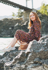 Young woman in dress and felt hat on horochowski bridge on katun river, altai