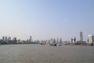 Cityscape by river against sky