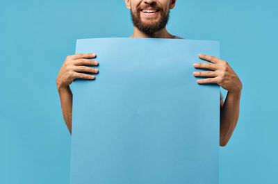 Midsection of man holding hands against blue background