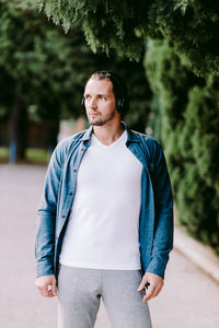 Handsome man listening music while standing in park