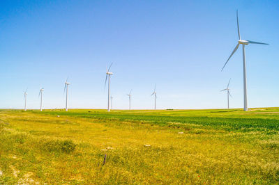 Windmills on field against clear sky