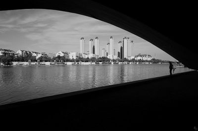 View of buildings by river against sky