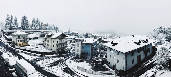 High angle view of snow covered houses and trees against sky