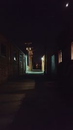 Empty narrow road along buildings at night