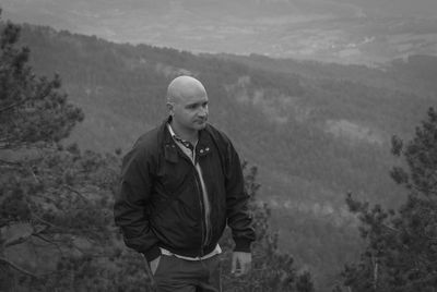 Man looking away while standing against landscape