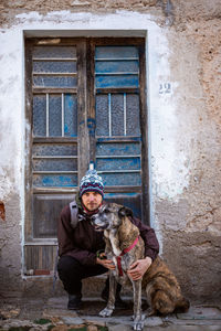 Portrait of young man sitting outdoors with dog