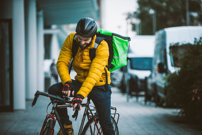 Man standing with bicycle on street in city